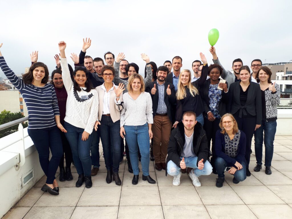 Groupe de collaborateurs posant ensemble en extérieur.